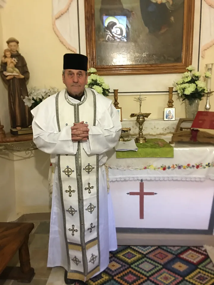 His Grace Mgr Andrea de Lucia in white liturgical vestments, in a chapel